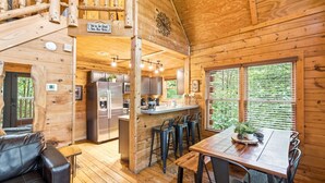 A wooden cabin interior with a kitchen, dining area, and a staircase. - Little Woods Cabin | Family-Friendly w/ Games! (Sevierville)