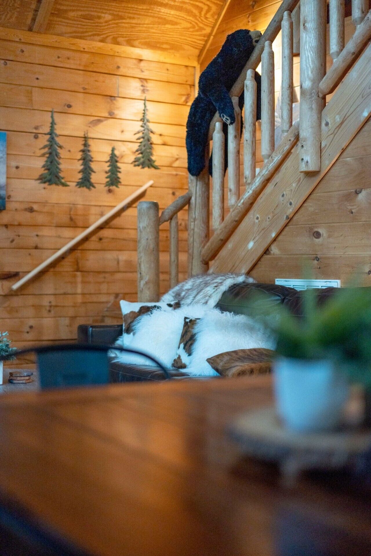 A wooden staircase inside a cabin with a log wall and a small pool area at the bottom.