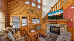 Ein Blockhaus-Interieur mit Kamin, Fernseher und Treppe.