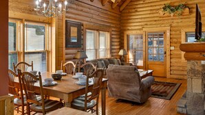 Ein Holzhaus-Interieur mit Essbereich, einer Couch und einem Kamin.