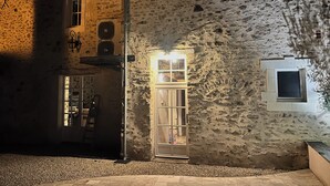 A stone building with a door and windows, a ladder, and a small window with a view of the interior. - La Pierre du Bonheur" village house for 2 to 8 people (Saint-Denis-d'Anjou)