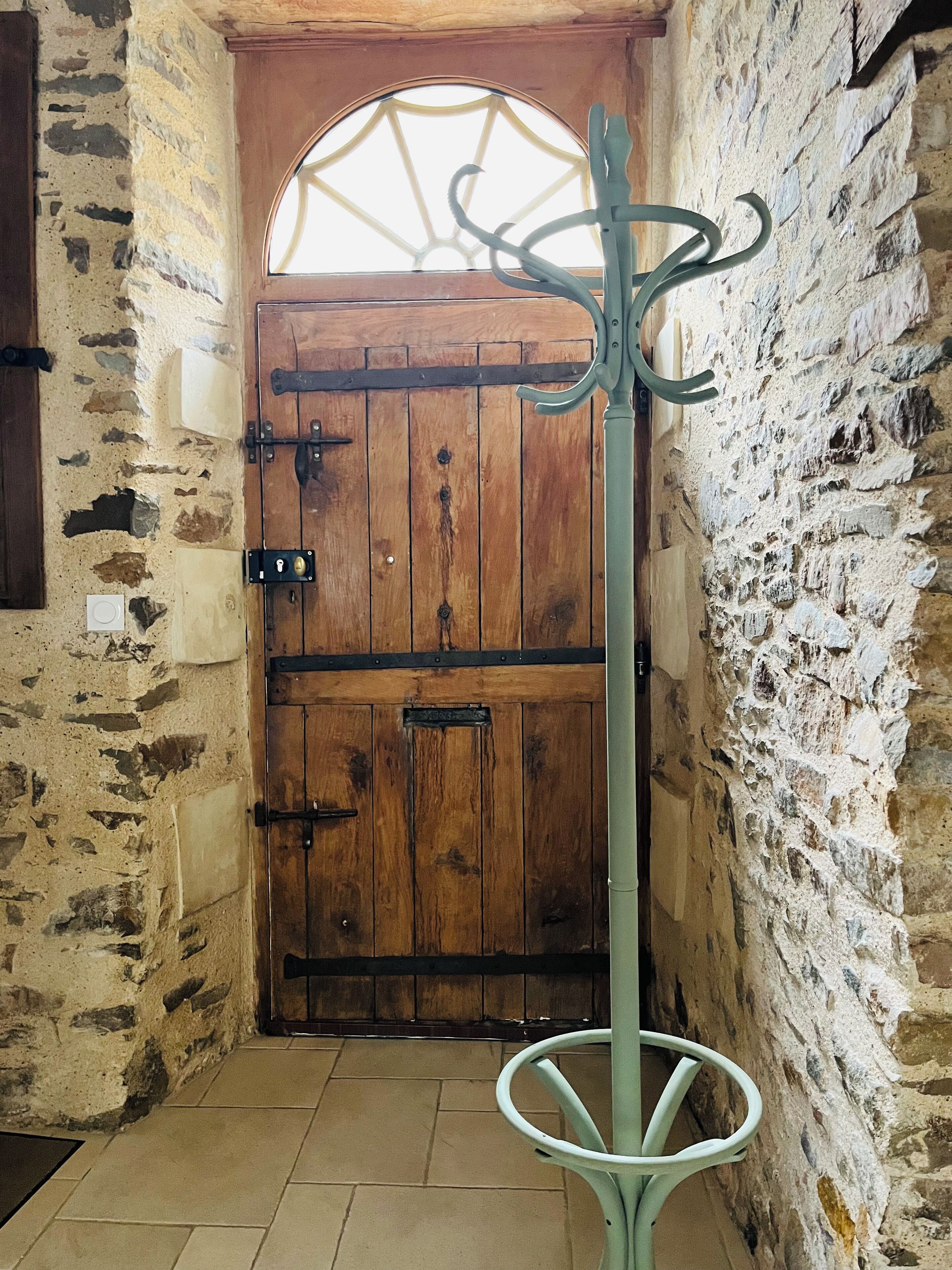 A rustic wooden door with a metal latch and a small window above it.