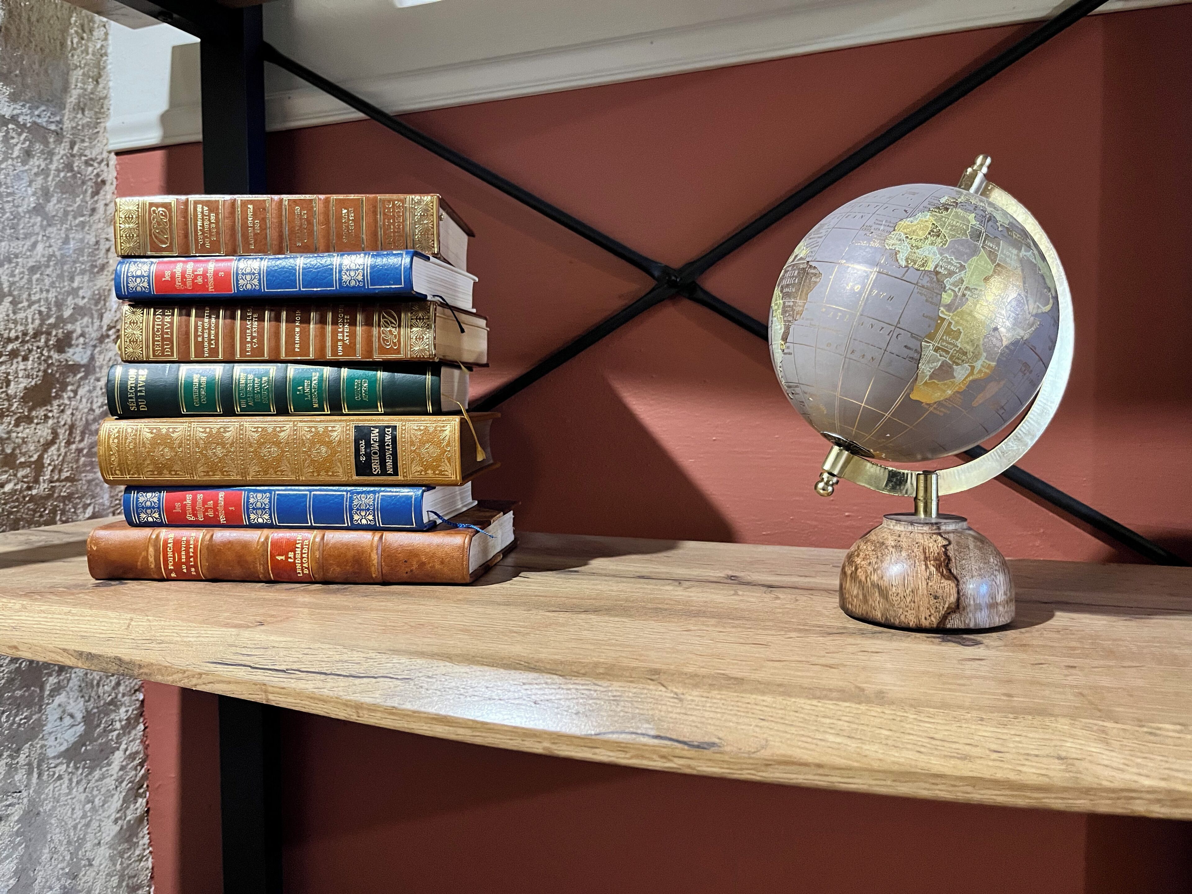 Un estante de madera con una pila de libros y un globo terráqueo.