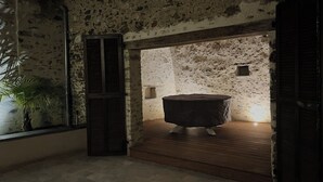 A rustic room with a stone wall, a wooden bench, and a small table. - La Pierre du Bonheur" village house for 2 to 8 people (Saint-Denis-d'Anjou)