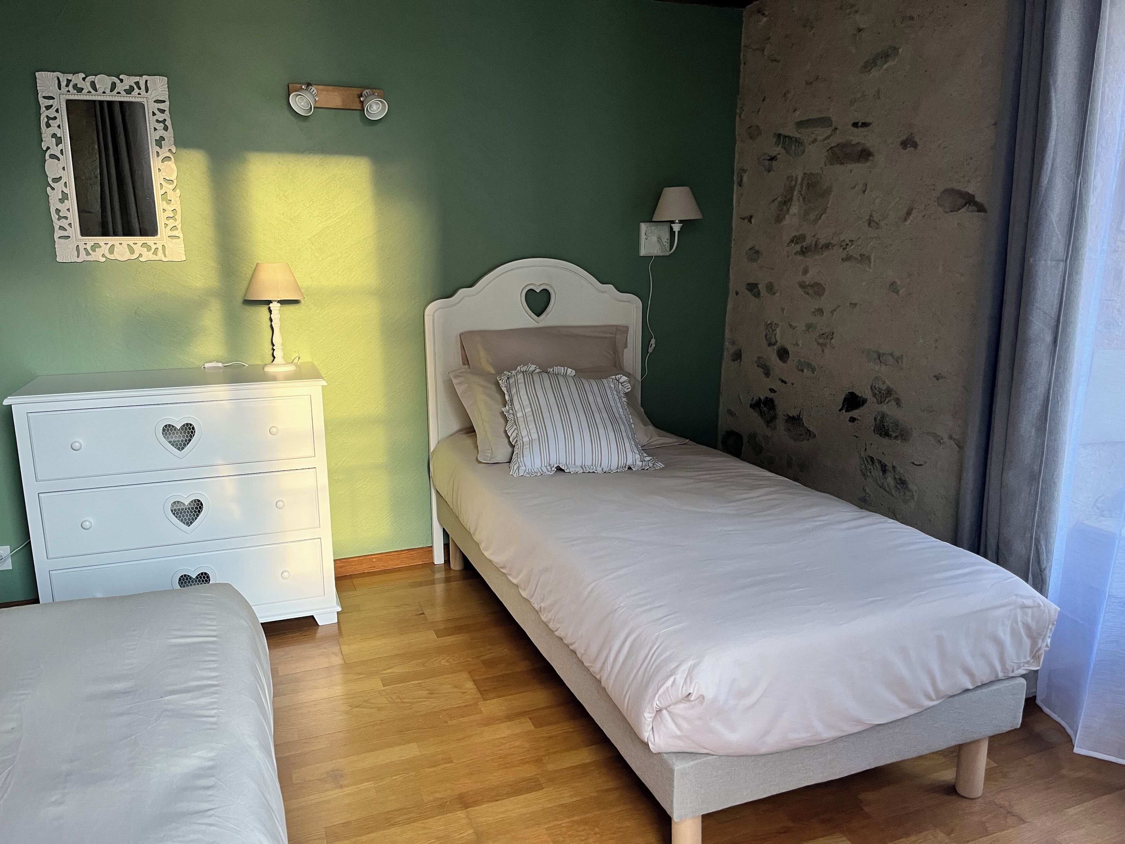 A bedroom with a bed, a dresser, a mirror, and a lamp.