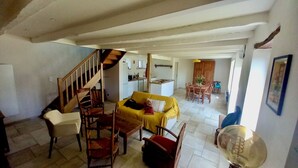 A spacious living area with a staircase, a yellow sofa, wooden chairs, and a dining table. - Typical Breton house between the Gulf of Morbihan and the ocean (Pluneret)