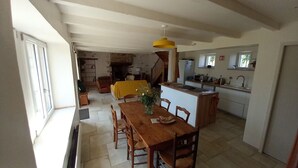 A spacious dining area with a wooden table and chairs, a yellow tablecloth, and a vase with flowers. - Typical Breton house between the Gulf of Morbihan and the ocean (Pluneret)