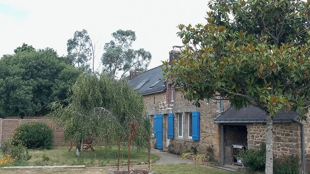 A stone house with blue shutters, a garden with a tree, and a stone wall in the background. - Typical Breton house between the Gulf of Morbihan and the ocean (Pluneret)
