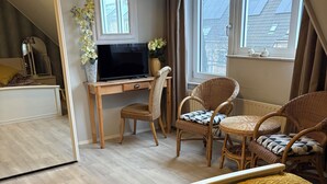 Een slaapkamer met een bed, een bureau en twee rieten stoelen.