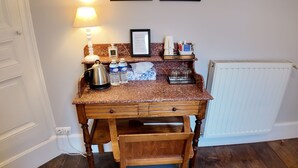 A kitchen with a wooden table, chairs, a kettle, water bottles, a coffee maker, and framed pictures on the wall. - Comfortabele en charmante kamer Montravel in de nummer 1 B&B van Ribérac. (Ribérac)