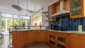Una cocina moderna con armarios de madera, salpicadero de azulejos azules y un ventanal grande.