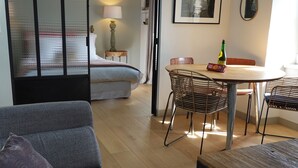 Et moderne hotelværelse med en seng, spiseplads med stole, et bord og en lampe.