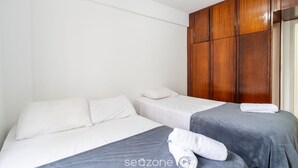 Ein Hotelzimmer mit zwei Betten, einem Holzschrank und einer weißen Wand.