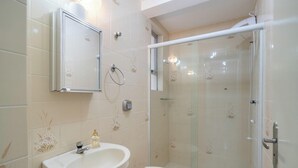 Ein Badezimmer mit Dusche, Toilette, Waschbecken und Spiegel.