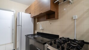 Eine Küche mit schwarzer Arbeitsplatte, einem weißen Kühlschrank, Holzschränken und einem Gasherd.