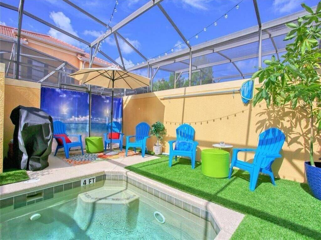 An indoor pool area with artificial grass, blue chairs, and a glass ceiling.