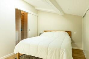 Ein Schlafzimmer mit Bett, Dusche und einer Tür zu einem Badezimmer.