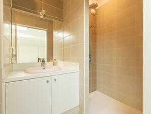 Ein Badezimmer mit Waschbecken, Spiegel und Dusche.