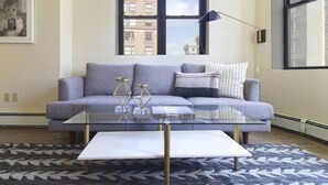 A modern living room with a grey sofa, a glass coffee table, and a patterned rug. - New to VRBO!  Awesome location downtown, closeby bars, restaurants + historic sites Walk Anywhere! (Boston)