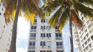 Un immeuble à plusieurs étages doté de balcons, entouré de palmiers.