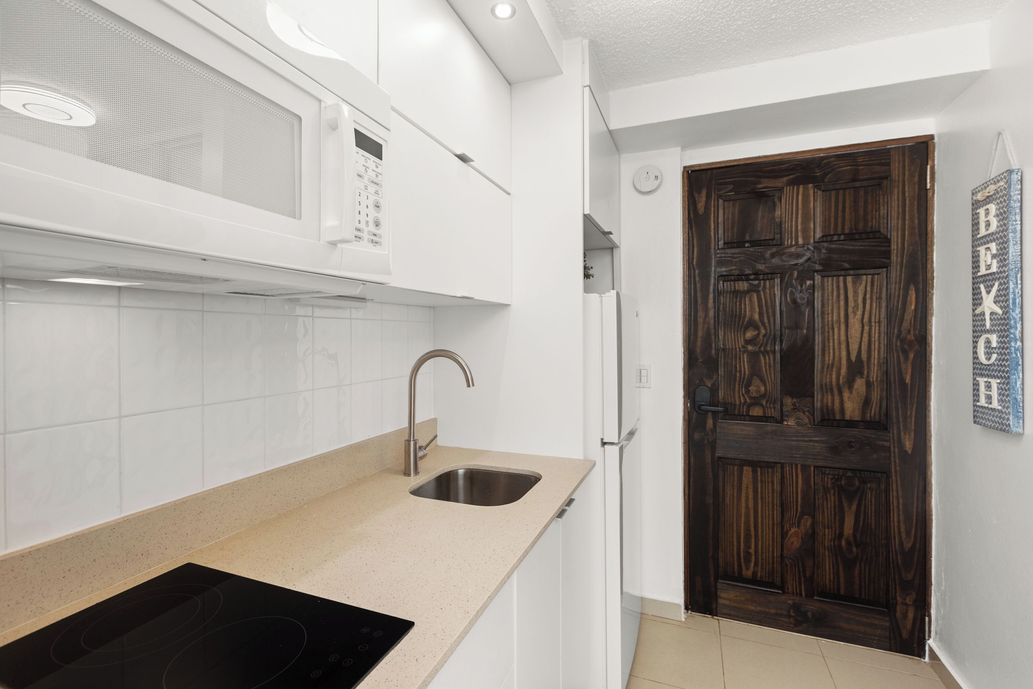 A modern kitchen with white cabinets, a stainless steel sink, and a black induction cooktop.