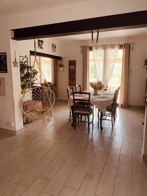 Een eetgedeelte met een ronde tafel, stoelen, een hangstoel en een houten balk.
