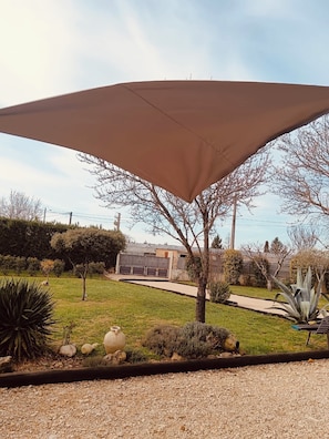 A garden with a large shade sail, a gravel path, and various plants. - Charming villa in Provence, calm and relaxation for 10 people (Carpentras)
