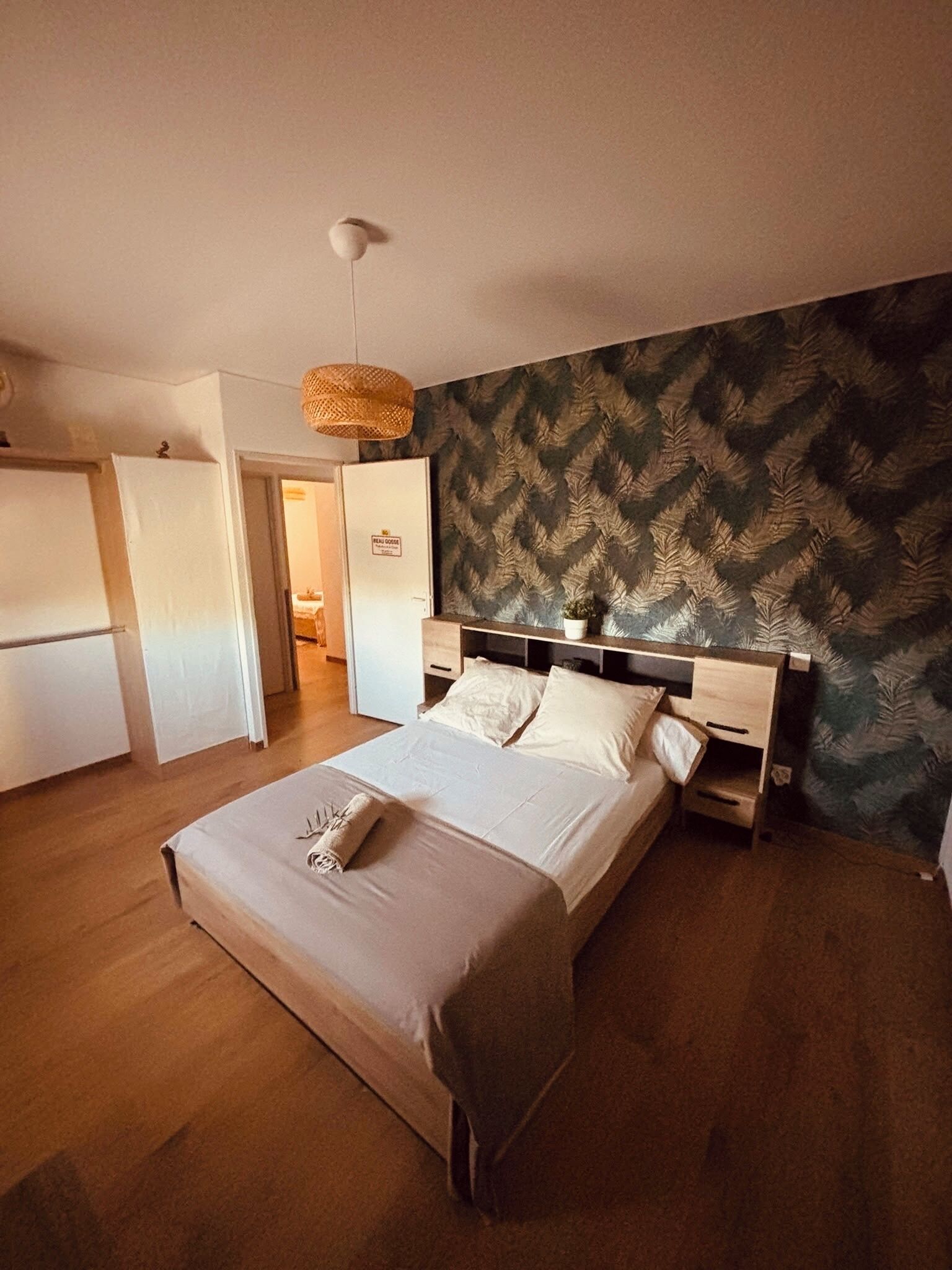A bedroom with a bed, bedside tables, a hanging light fixture, and a patterned wall.