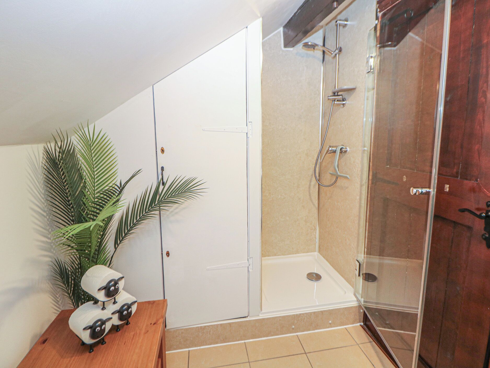 Un bagno con doccia, toilette e lavandino. Sul mobile si trova una pianta e una statuina decorativa a forma di pecora.