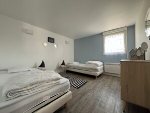 A bedroom with a large bed, a smaller bed, a desk, and a window. - Le Rameau, gite in the heart of the city, terrace, quiet street close to the Old Port. (Pornic)