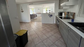 A kitchen with a central island, a dining area with a sofa, and a view of the outdoors. - Le Rameau, gite in the heart of the city, terrace, quiet street close to the Old Port. (Pornic)