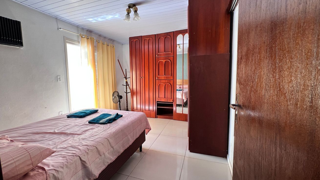 A bedroom with a bed, a wardrobe, and a door leading to another room.
