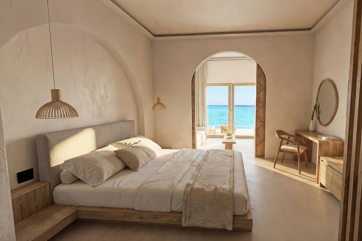Un dormitori amb un llit gran, una taula de treball i vistes al mar.