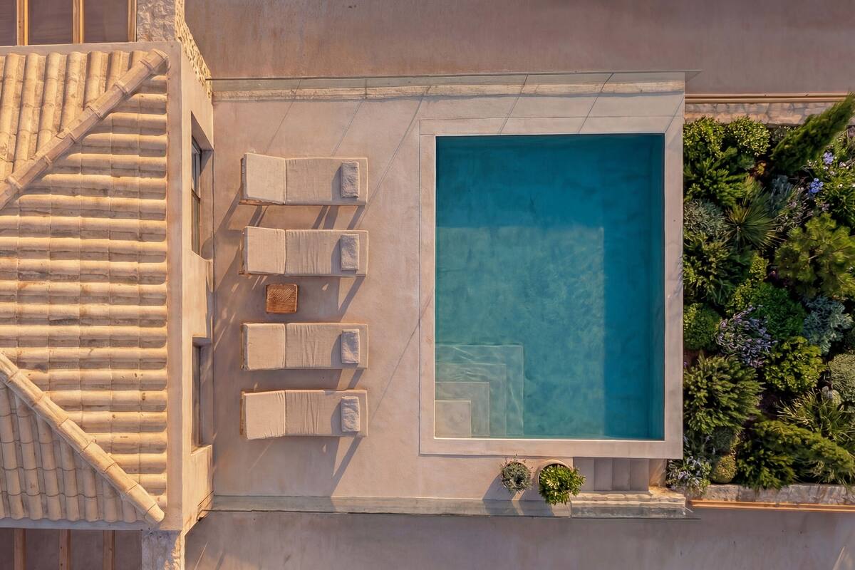 Vista aèria d'un hotel amb piscina, gandules i teulada enrajolada.