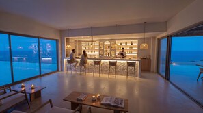 A modern bar area with a bar counter, seating, and a view of the ocean. - VedoMare Hotel & Suites (Zakynthos)