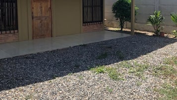 Una edificación de un solo nivel con techo plano, un porche cubierto y un camino de entrada de grava.