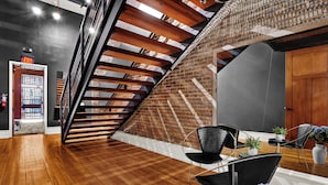 Een modern interieur met een houten trap, een bakstenen muur en een zithoek met stoelen en een tafel.