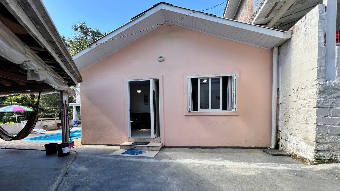 Um edifício térreo com fachada rosa, uma porta e uma janela.