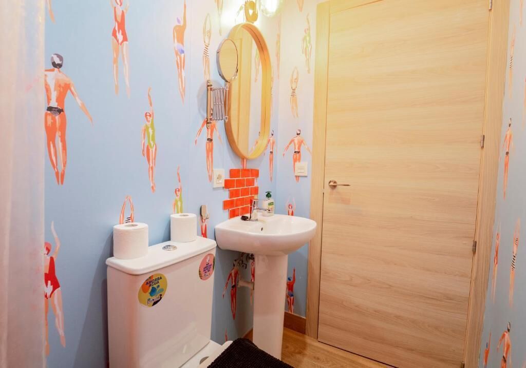 Un baño con inodoro, lavamanos y puerta de madera.