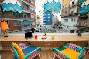A room with a wooden desk, two colorful chairs, a laptop, a red mug, and a yellow mug. - Guesthome Lemon & Green (Granada)