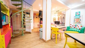 A vibrant children's play area with a spiral staircase, a dining area with yellow chairs, and a green sofa. - Guesthome Lemon & Green (Granada)