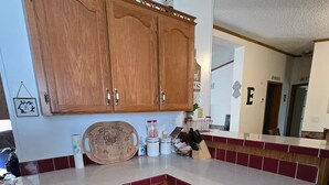 Cocina con armarios de madera, encimera de mármol y un tablero decorativo con pavo.