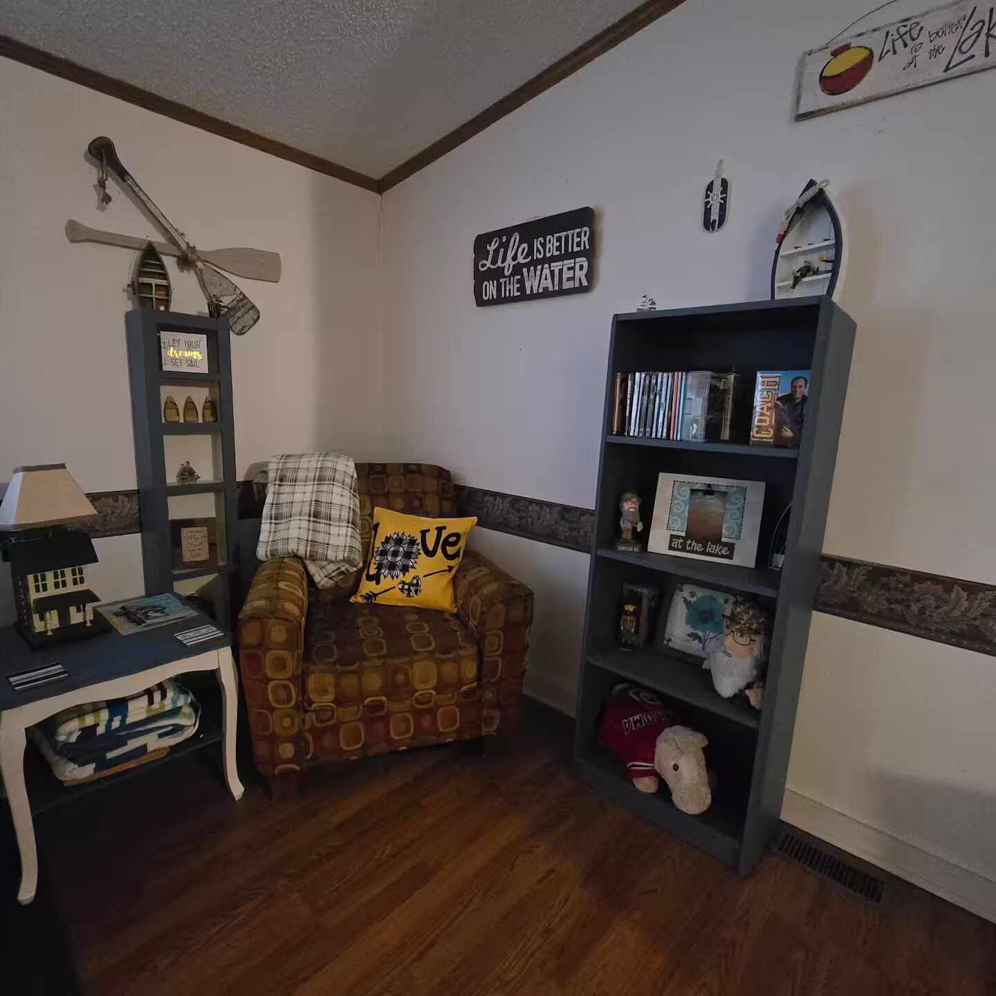 Un salón acogedor con un sillón estampado, una estantería y una pared con citas inspiradoras.