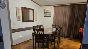 Un comedor con una mesa y sillas de madera, un espejo y decoración en la pared.