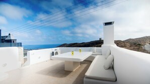 A rooftop terrace with a white table, white sofa, and yellow candles. - Akrotiri Castle View (Santorini)