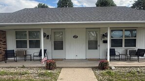 A single-story building with a front porch, two windows on each side, and a welcome sign.