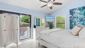 Ein Schlafzimmer mit Bett, Deckenventilator, Fernseher und Blick ins Freie.