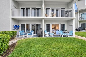 A two-story residential building with a balcony, outdoor seating area with chairs, and a covered patio. - Southeaster B101 (New Smyrna Beach)