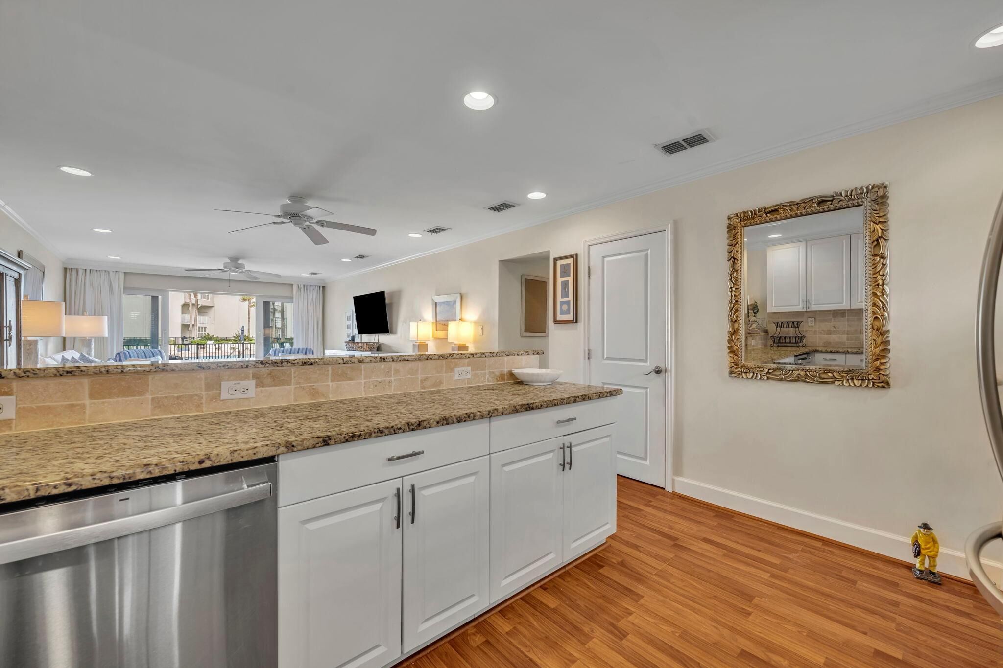 A modern kitchen with granite countertops, white cabinetry, and a built-in dishwasher.