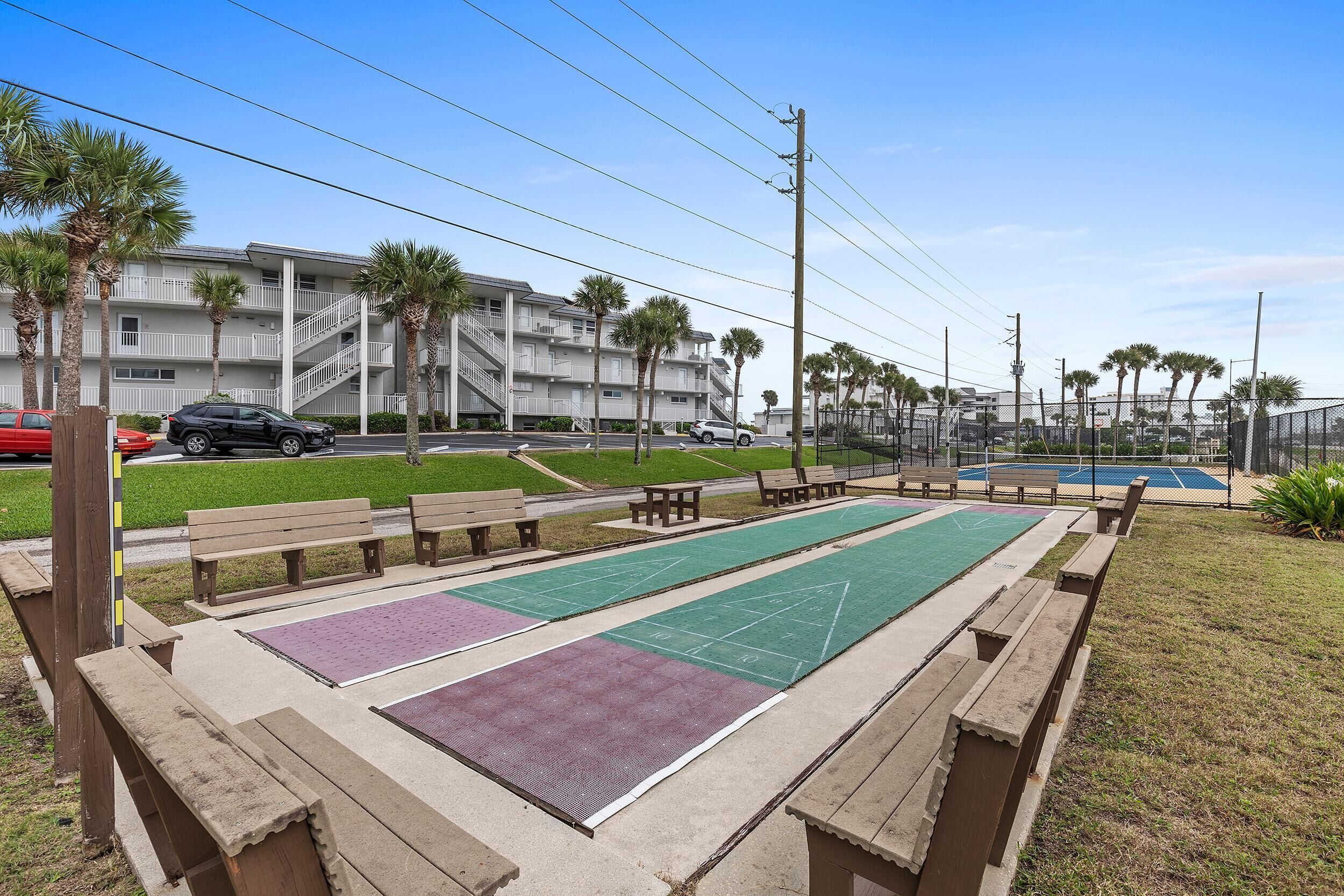 Un patio con mesas de juego de hojalata, bancos y una cancha de tenis.